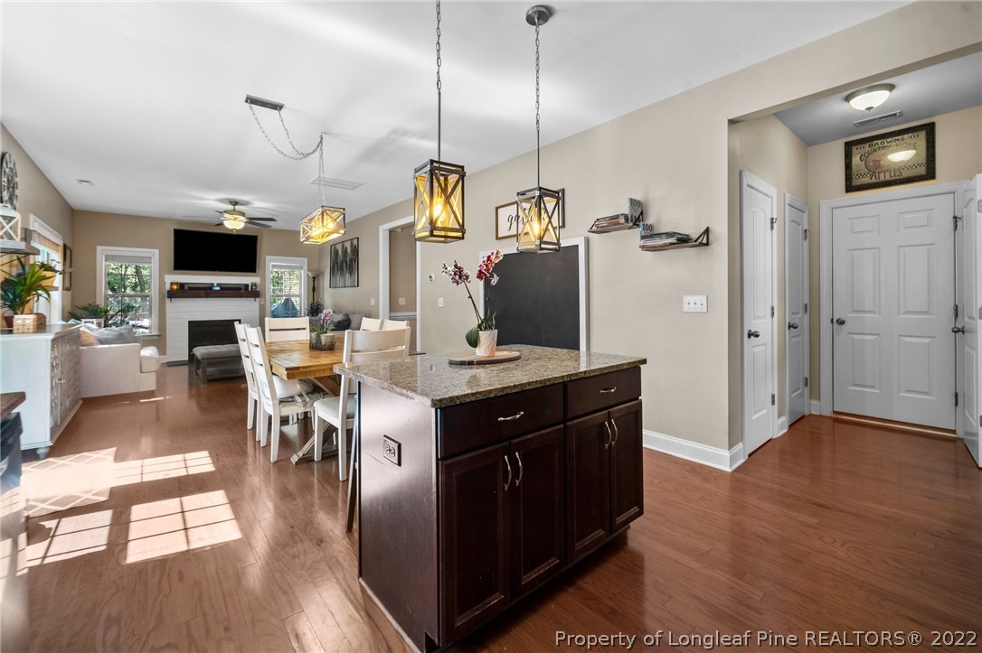 228 Culpepper Road Cameron, NC 28326 - Photo 13 of 36 a kitchen with stainless steel appliances kitchen island granite countertop a stove a refrigerator a sink a dining table and chairs with wooden floor