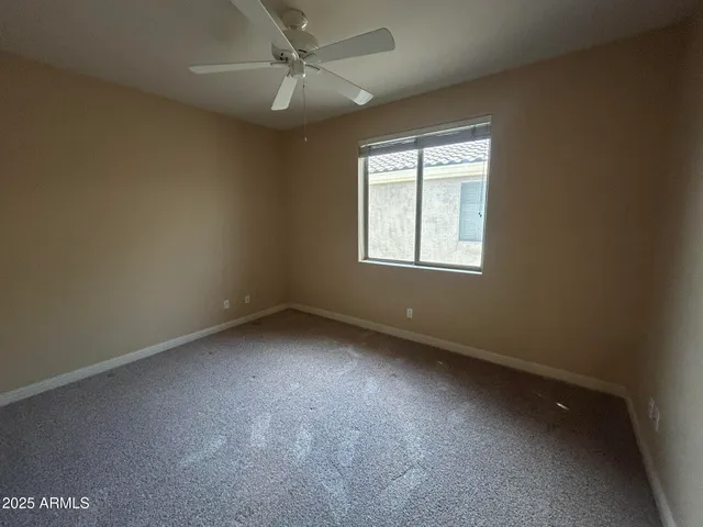 an empty room with a ceiling fan and a window