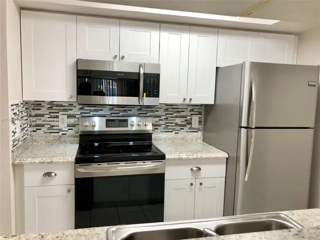 a kitchen with stainless steel appliances granite countertop a stove a refrigerator and a microwave