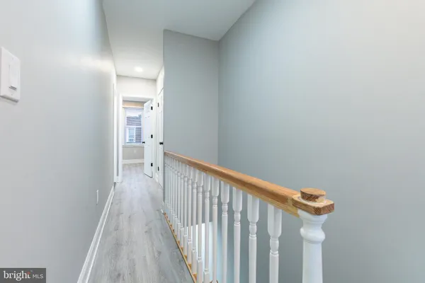 a view of a hallway with wooden floor and a bathroom