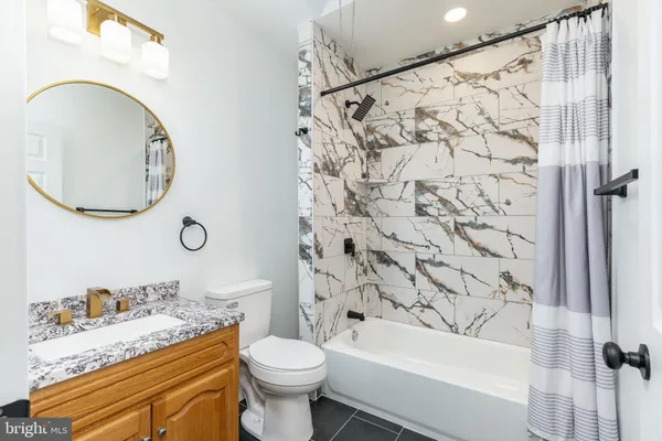 a bathroom with a granite countertop toilet sink and mirror