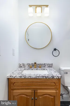 a bathroom with a granite countertop toilet sink mirror and vanity