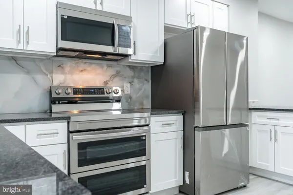 a kitchen with stainless steel appliances white cabinets and a refrigerator