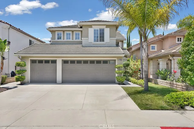 a front view of a house with a garden and palm trees