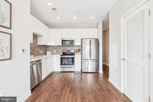 a kitchen with a refrigerator a stove top oven and wooden floor