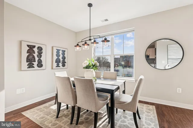 a dining room with furniture a potted plant and wooden floor