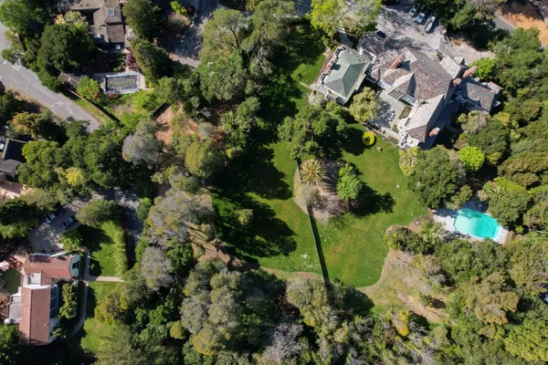 an aerial view of residential house with outdoor space and trees all around