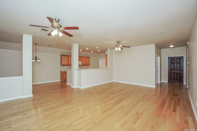 a view of empty room with wooden floor and ceiling fan