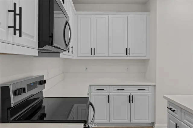 a kitchen with granite countertop white cabinets and stainless steel appliances