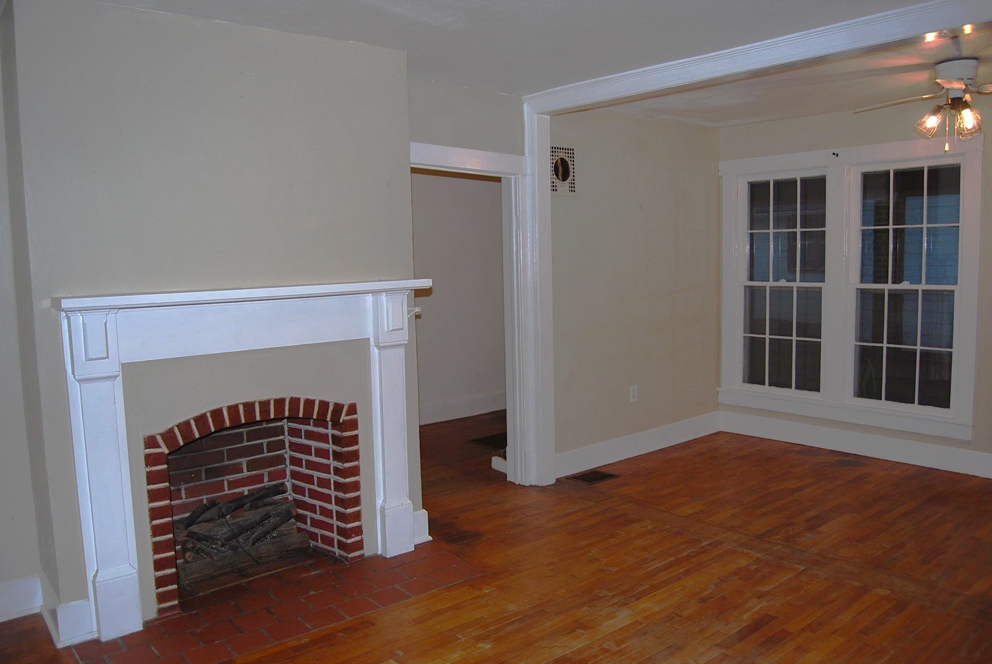892 Virginia Avenue Goshen, VA 24439 - Photo 4 of 24 an empty room with wooden floor a fireplace and windows