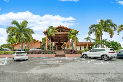 a front view of a building with lot of cars and trees