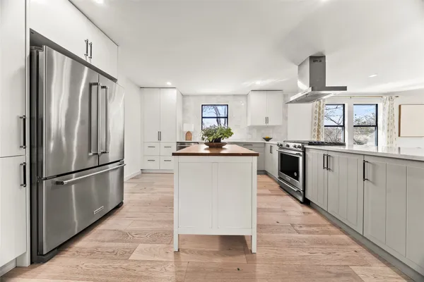 a kitchen with stainless steel appliances granite countertop a refrigerator a stove a sink dishwasher and white cabinets with wooden floor