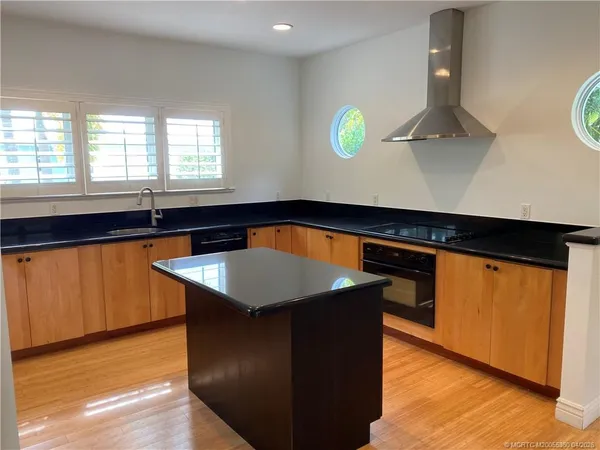 a kitchen with kitchen island granite countertop a sink a stove and wooden floor
