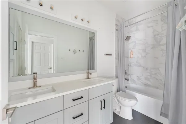 a bathroom with a double vanity sink toilet mirror and bathtub