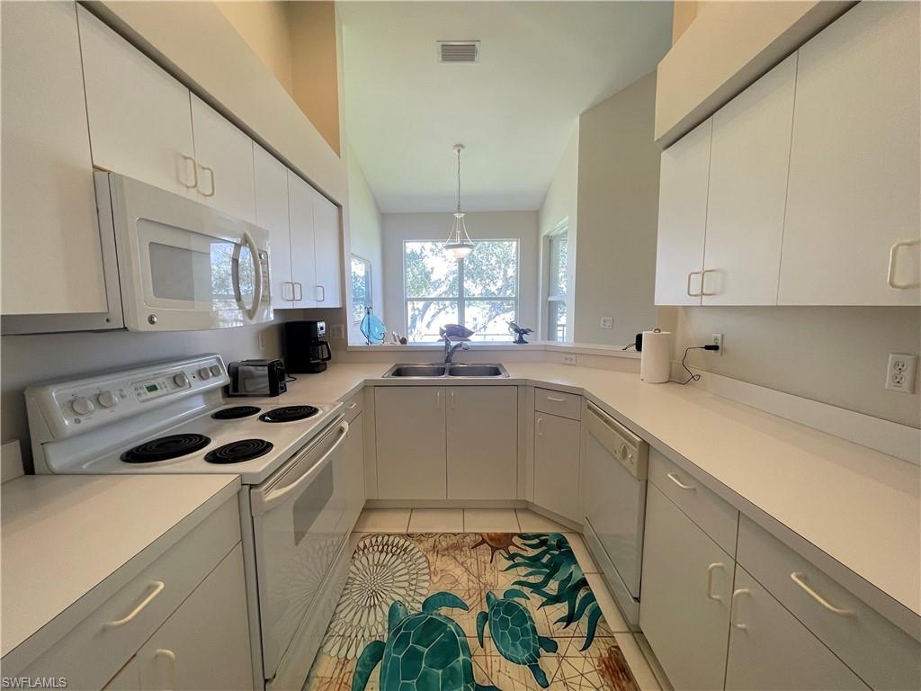 317 Sunrise Cay, Unit 204 Naples, FL 34114 - Photo 7 of 19 a kitchen that has a sink cabinets counter space and a window