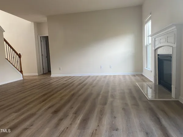 a view of empty room with wooden floor and fireplace