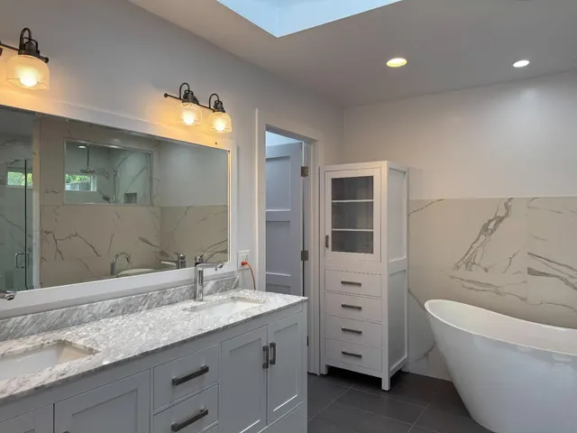 a bathroom with a granite countertop sink tub and mirror