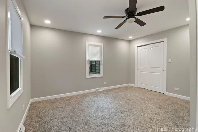 an empty room with windows and fan