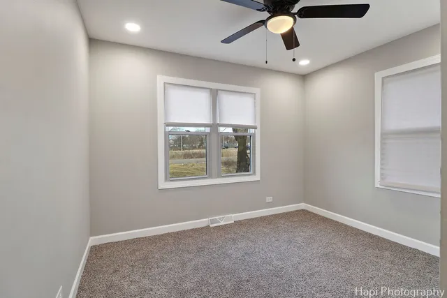 an empty room with windows and fan