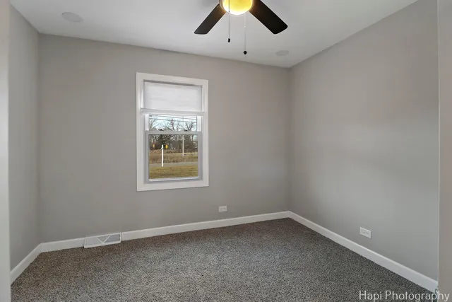 an empty room with a window and a ceiling fan