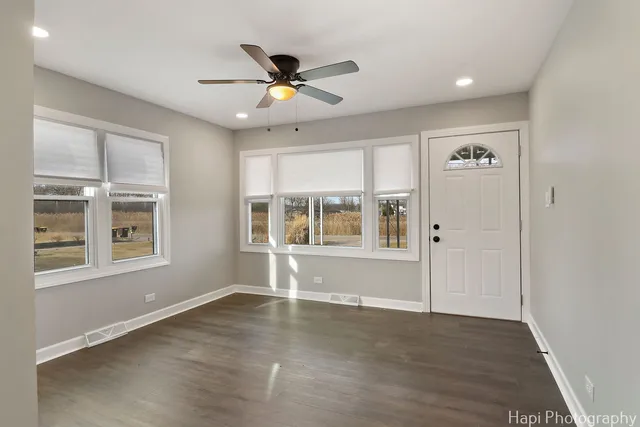 a view of an empty room with a window and wooden floor