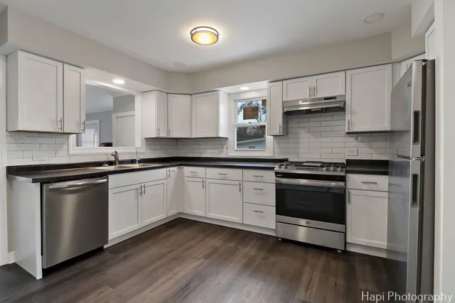 a kitchen with stainless steel appliances granite countertop a sink a stove a microwave and cabinets