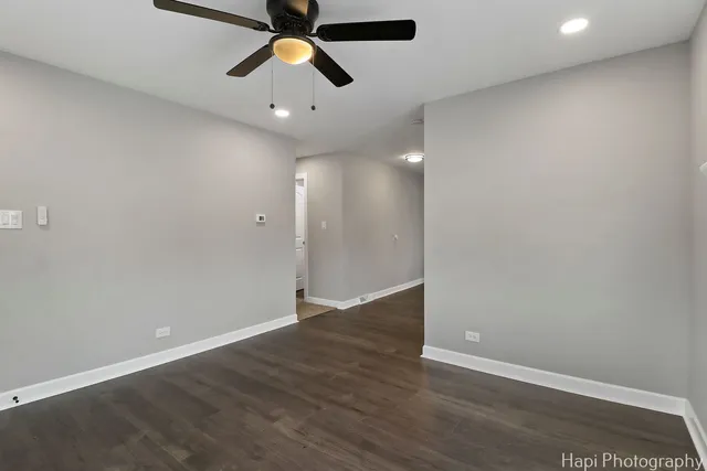 an empty room with wooden floor ceiling fan and window