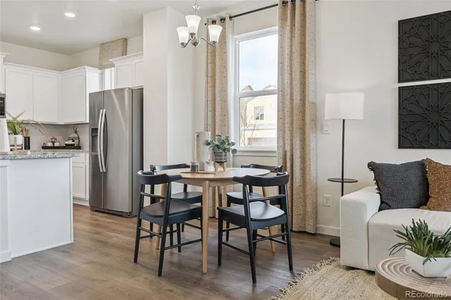 a kitchen with stainless steel appliances granite countertop a dining table chairs refrigerator and sink