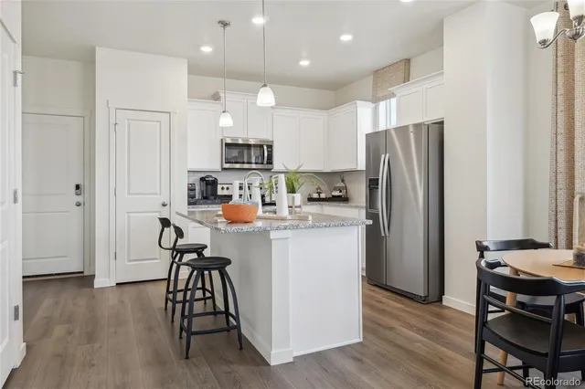 a kitchen with stainless steel appliances a refrigerator a stove a sink dishwasher and a refrigerator with wooden floor