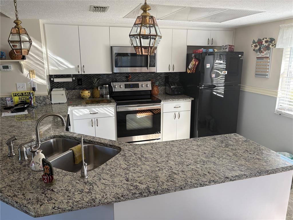5338 Spanish Trail Holiday, FL 34690 - Photo 9 of 34 a kitchen with stainless steel appliances granite countertop a sink a stove and a refrigerator