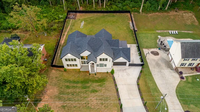 an aerial view of a house with swimming pool and large trees
