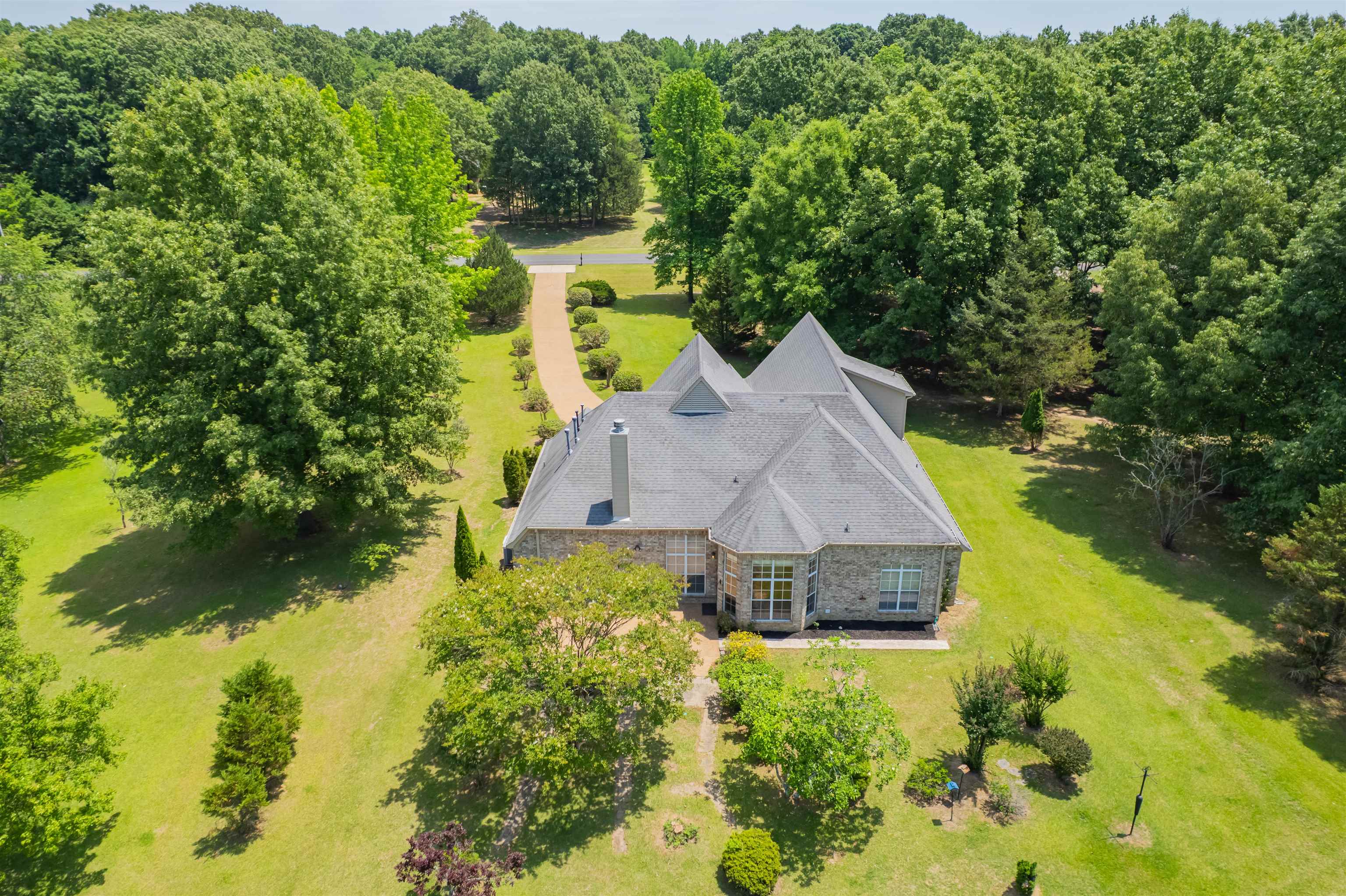 5035 Brian Ridge Road Arlington, TN 38002 - Photo 28 of 40 Stone exterior with a gray shingle roof, surrounded by expansive green lawns and mature trees