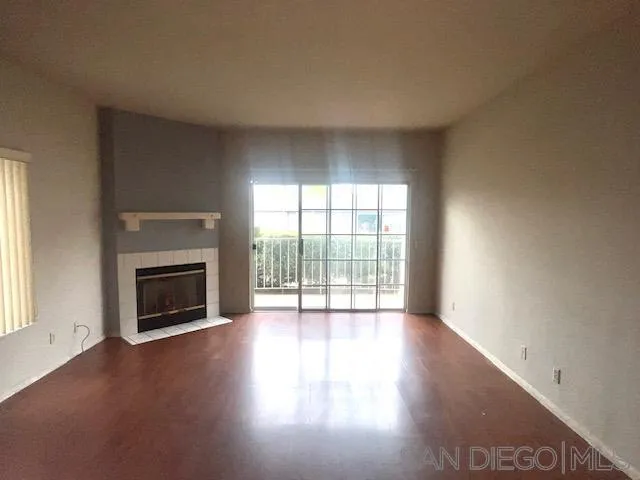 13802 Midland Road Poway, CA 92064 - Photo 3 of 12 an empty room with wooden floor fireplace and windows