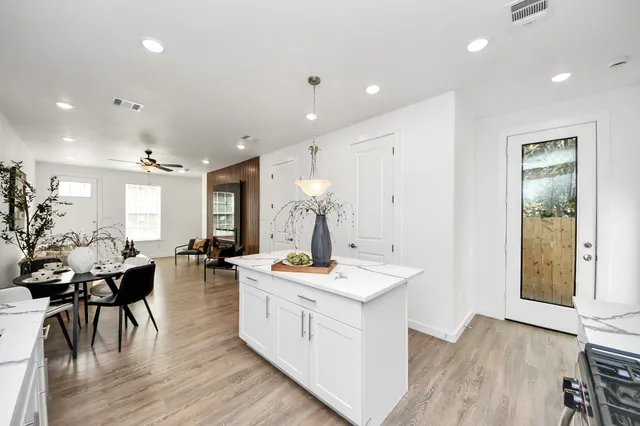 a large white kitchen with sink a stove a dining table and chairs