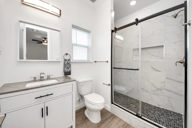 a bathroom with a shower sink vanity mirror and toilet