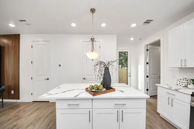 a kitchen with a sink dishwasher and white cabinets with wooden floor