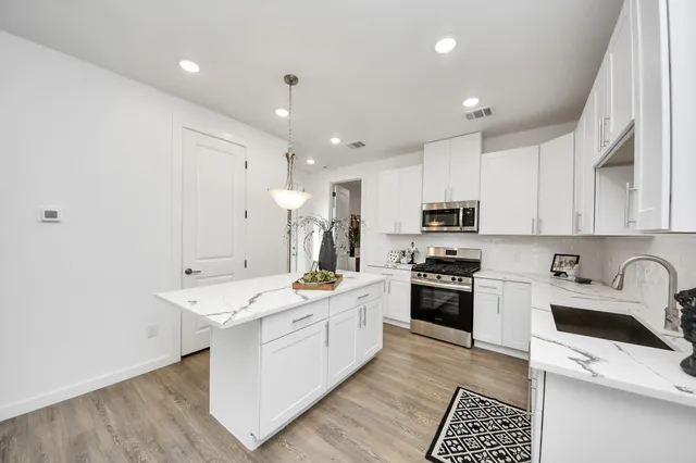 a kitchen with a sink a stove a refrigerator and white cabinets