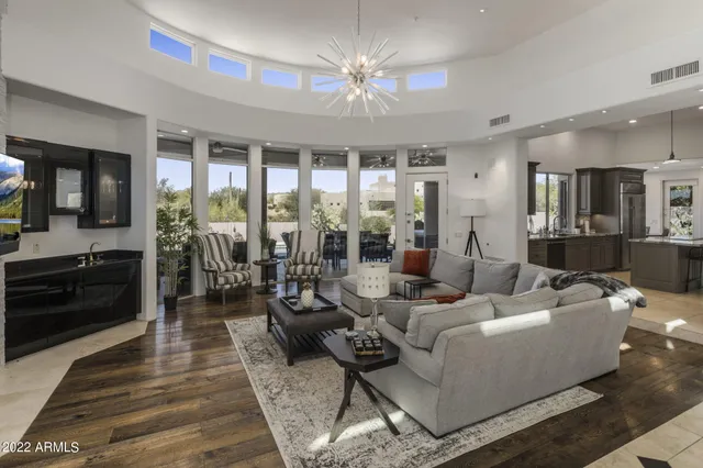 a living room with furniture large windows and wooden floor