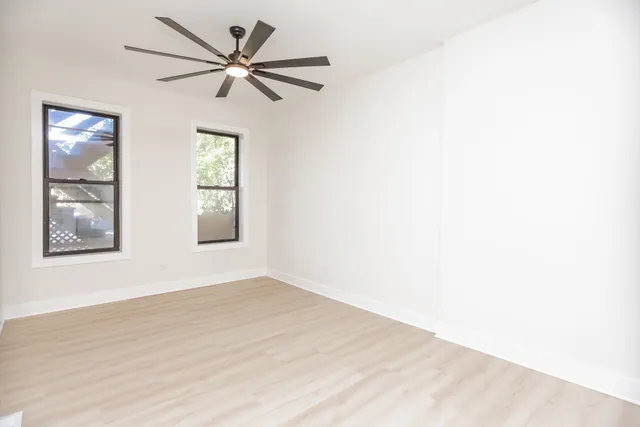 a view of an empty room with window and wooden floor
