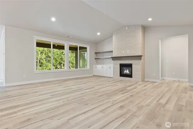 an empty room with wooden floor a fireplace and windows