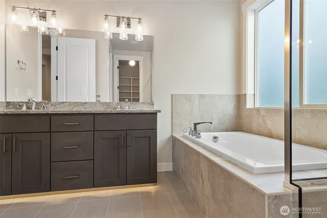 a bathroom with a tub a double vanity sink and mirror