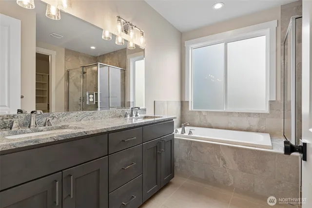 a bathroom with a granite countertop bathtub a sink and a large mirror