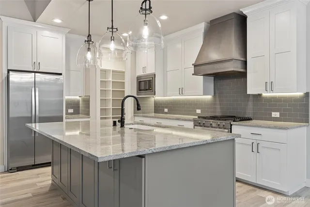 a kitchen with stainless steel appliances granite countertop a sink a stove and a refrigerator