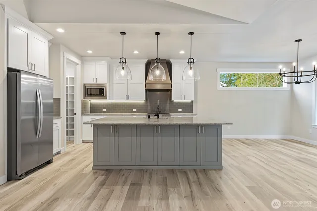 a kitchen with kitchen island granite countertop a sink cabinets and stainless steel appliances