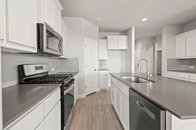 a kitchen with stainless steel appliances granite countertop a sink stove cabinets and refrigerator