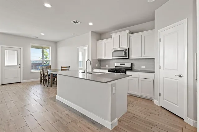 a kitchen with stainless steel appliances white cabinets a sink and a refrigerator