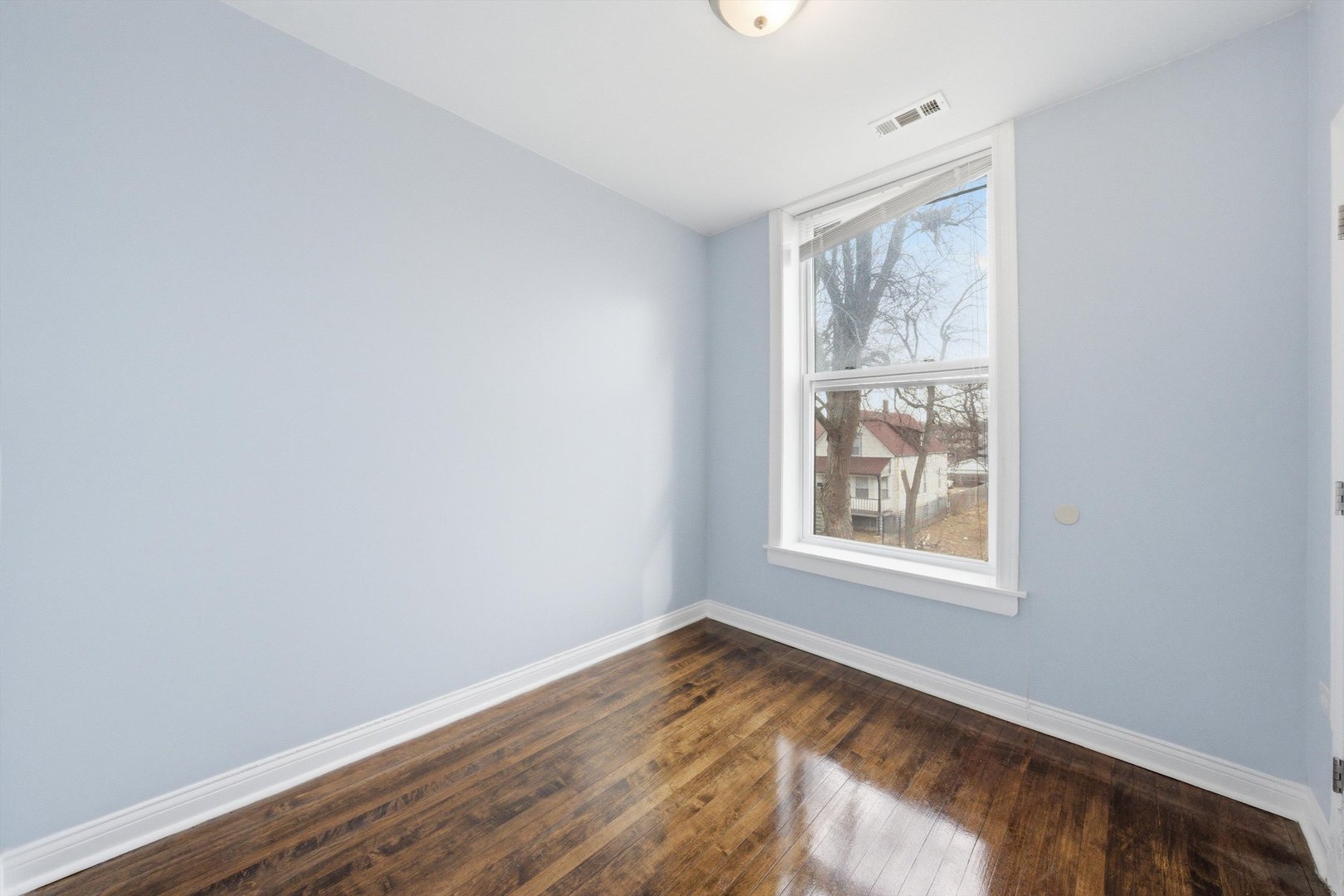 7242 South May Street, Unit 2 Chicago, IL 60621 - Photo 5 of 12 an empty room with wooden floor and windows