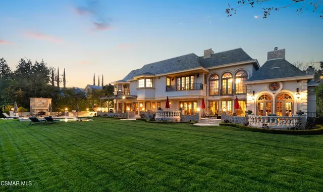 a view of a house with a big yard and large trees