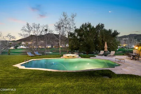 a view of pool with lawn chairs and a big yard