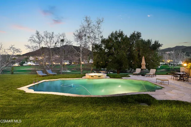 a view of pool with lawn chairs and a big yard